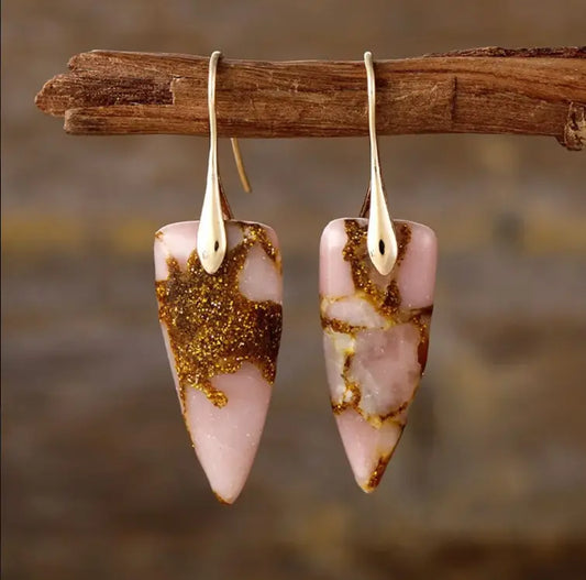 These raw stone drop earrings are featured on a rustic background. 
