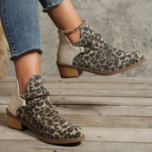 Leopard print ankle boots worn with rolled-up jeans on a wooden floor.
