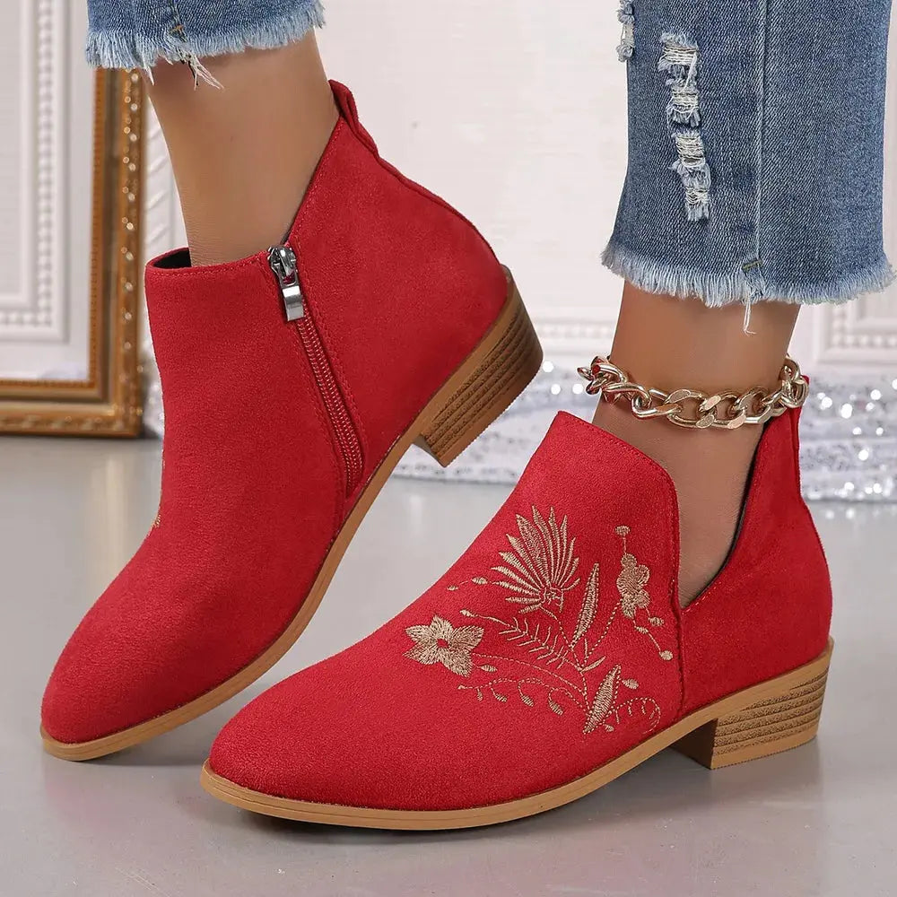 Red ankle boots with floral embroidery worn with denim jeans.