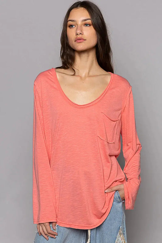 Woman wearing a coral long-sleeve top against a gray background.