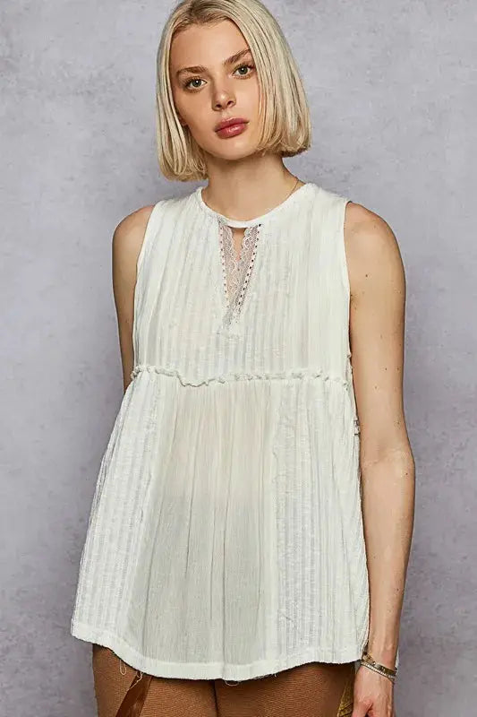 Woman wearing a white sleeveless top against a gray background.