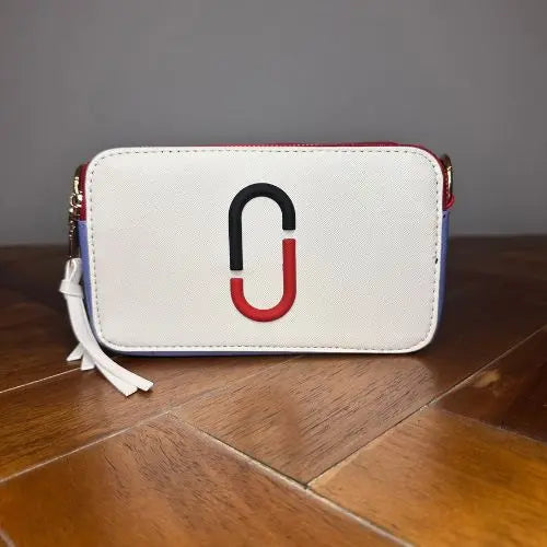 Channel the iconic style of Marc Jacobs with this Snapshot-inspired crossbody—a compact, structured silhouette that blends bold design with everyday function. Crafted from smooth faux leather, it features a dual-zip top closure and a color block palette that adds instant personality to any outfit.
