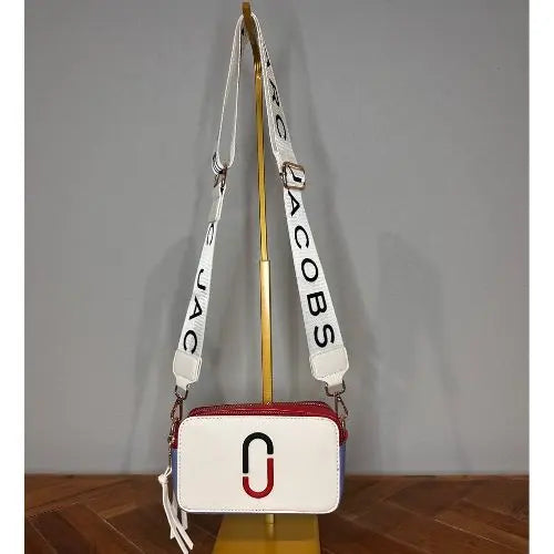 White handbag with a distinctive logo on a wooden surface