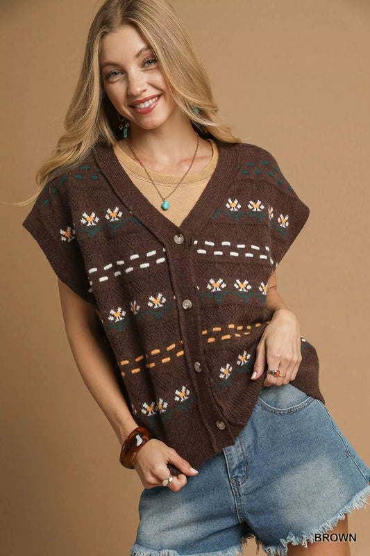 Woman wearing a brown patterned vest over a denim shirt against a beige background