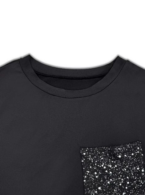Close up of the glitter front pocket on a black long sleeve top showing sparkle contrast.