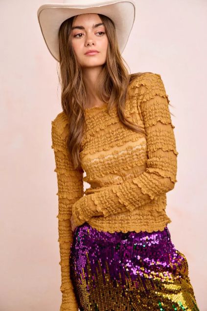 Mustard textured long sleeve top paired with a purple sequin skirt showing elevated styling with western inspiration.