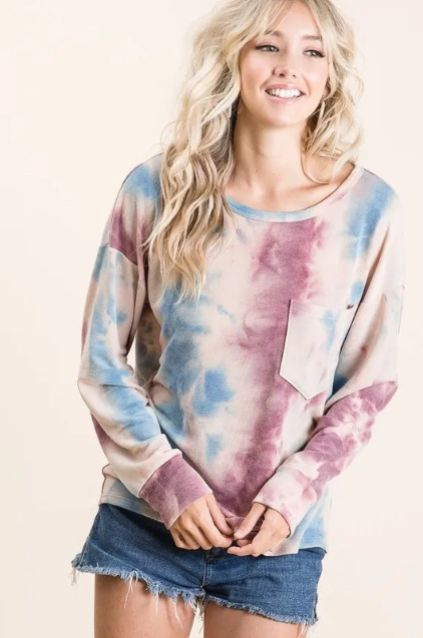 Model wearing a pastel tie dye long sleeve top with soft blue and mauve tones styled with a denim skirt for a relaxed everyday look.